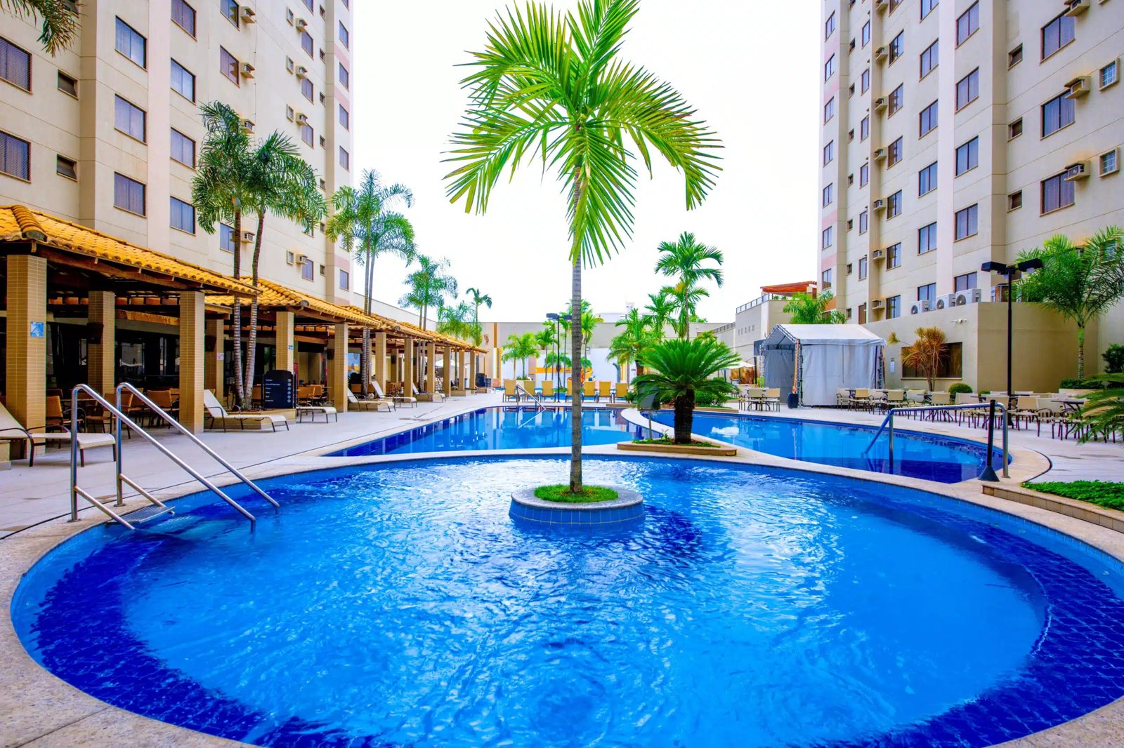 Piscina termal do Boulevard Suíte Hotel com ilha de coqueiros e espreguiçadeiras